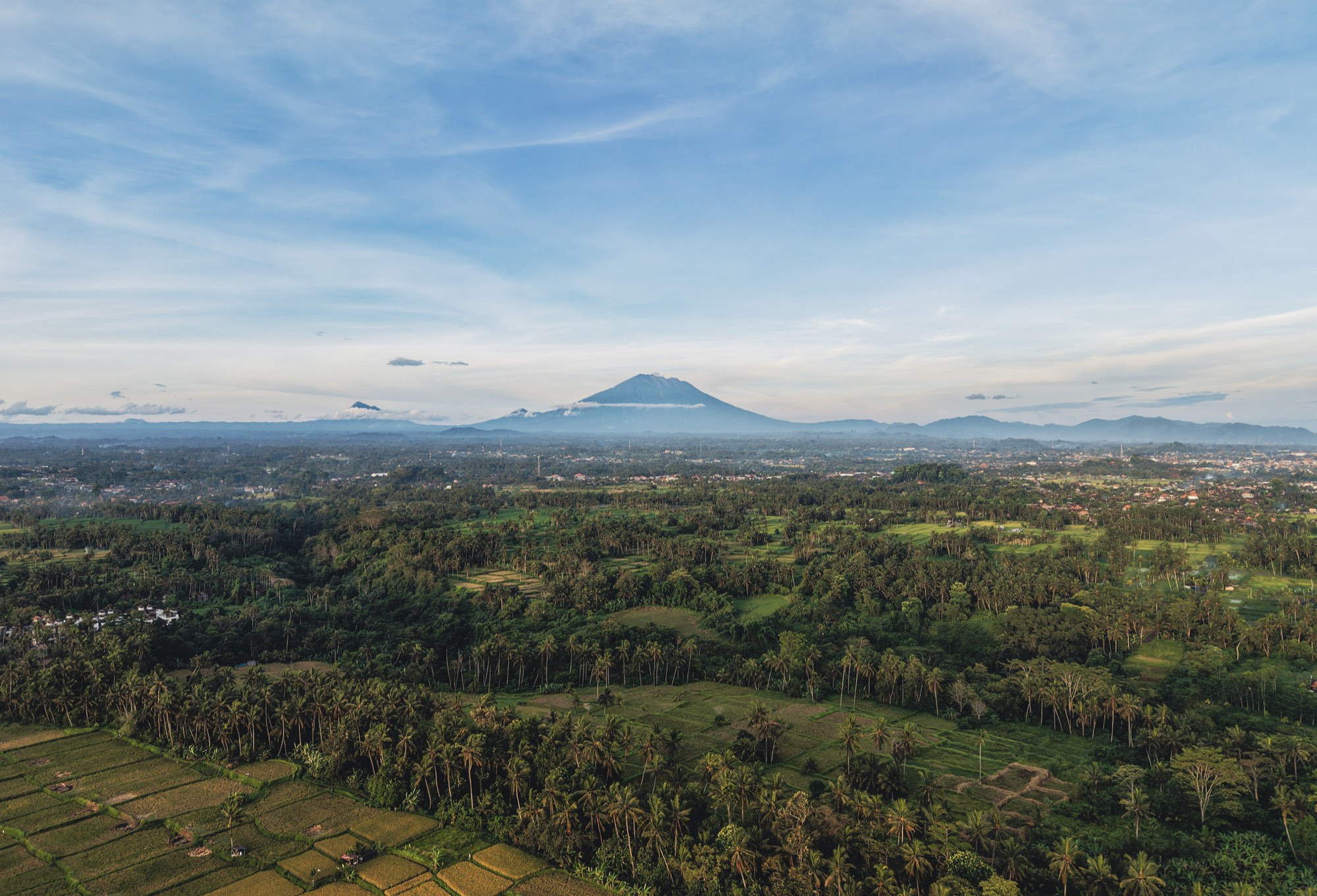 Mount Agung volcano rising over Bali's rice fields and palm groves